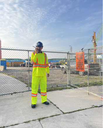 Security guard in high-visibility gear patrolling a fenced construction site
