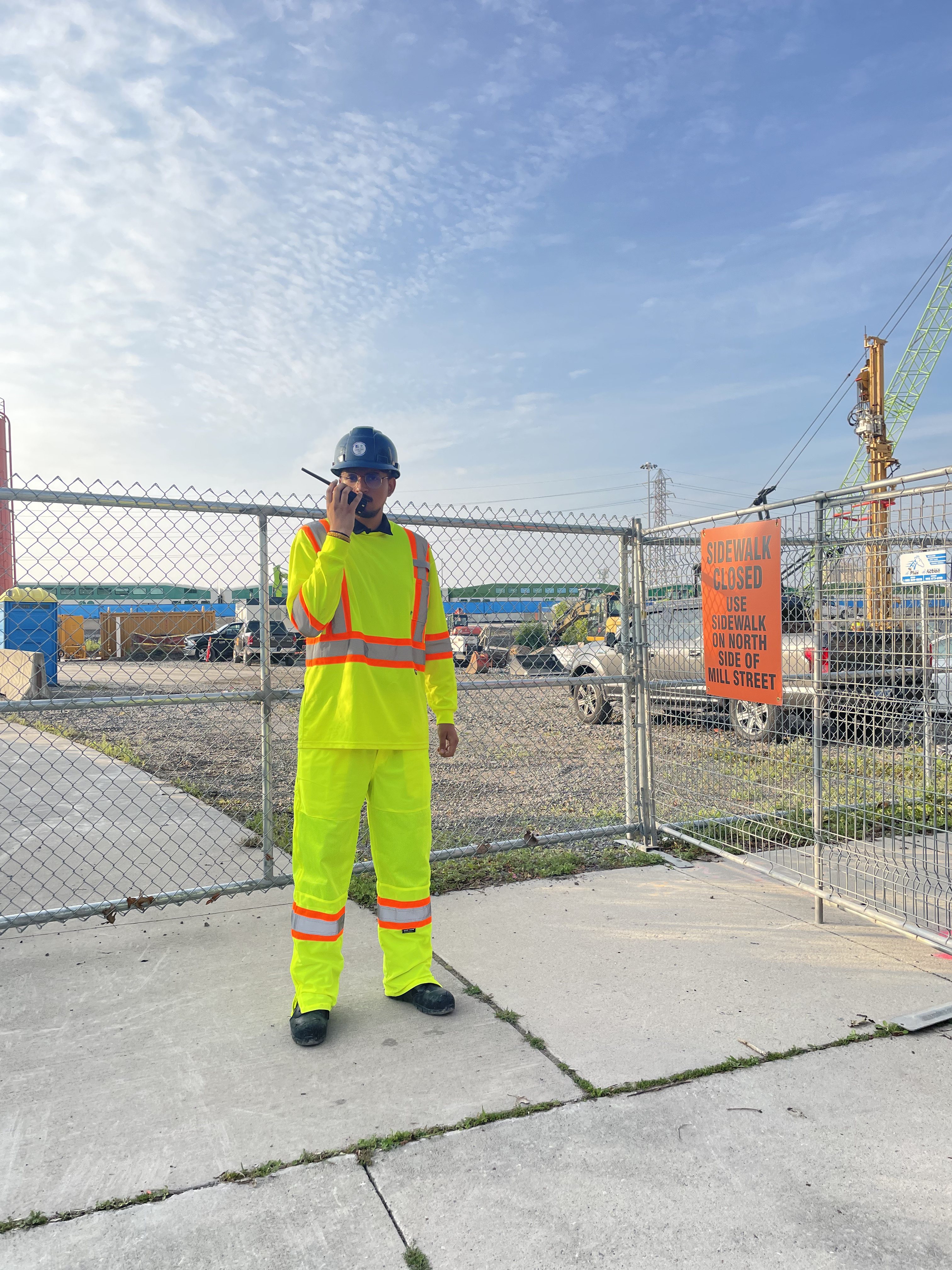 Security guard in high-visibility gear patrolling a fenced construction site